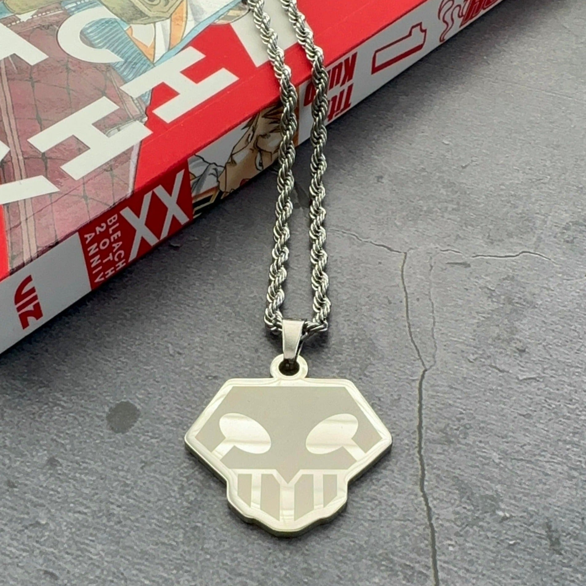 shinigami logo necklace laying on a manga book