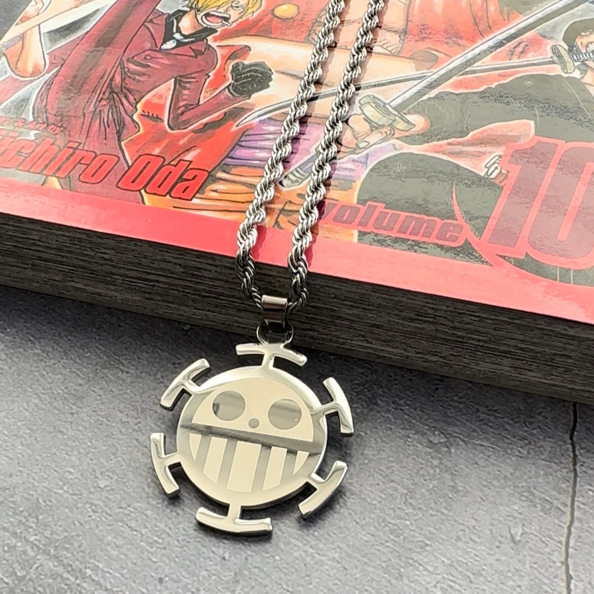 heart pirates logo necklace laying on a manga book 