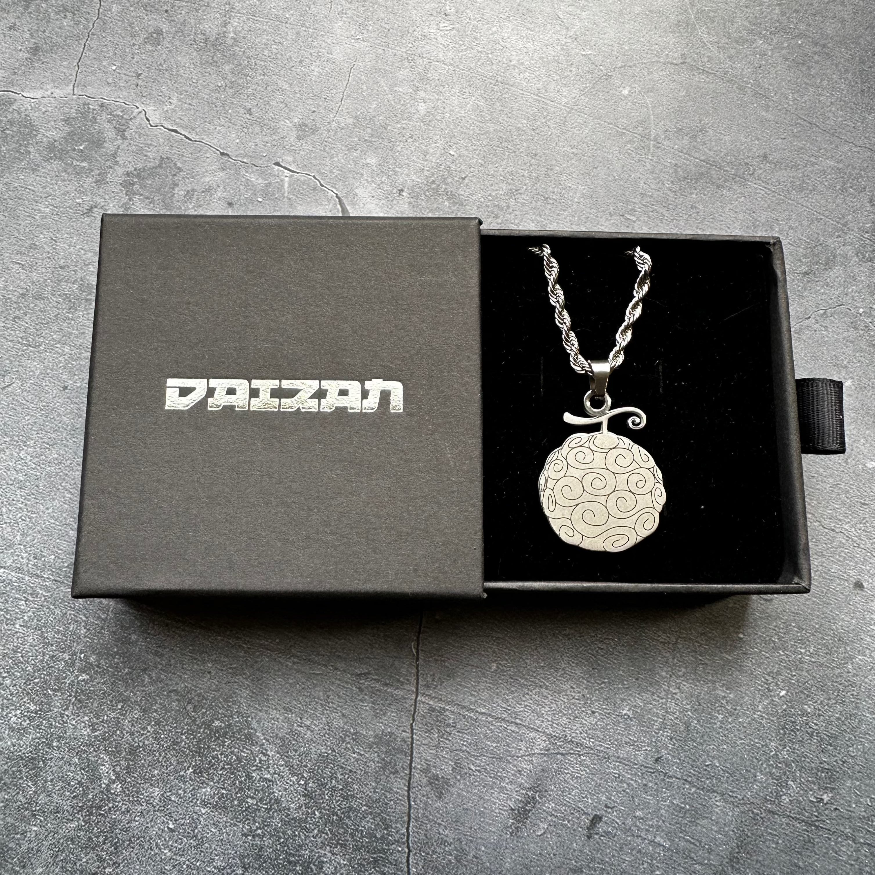 gumgum fruit necklace sitting in a branded jewelry box against a grey background